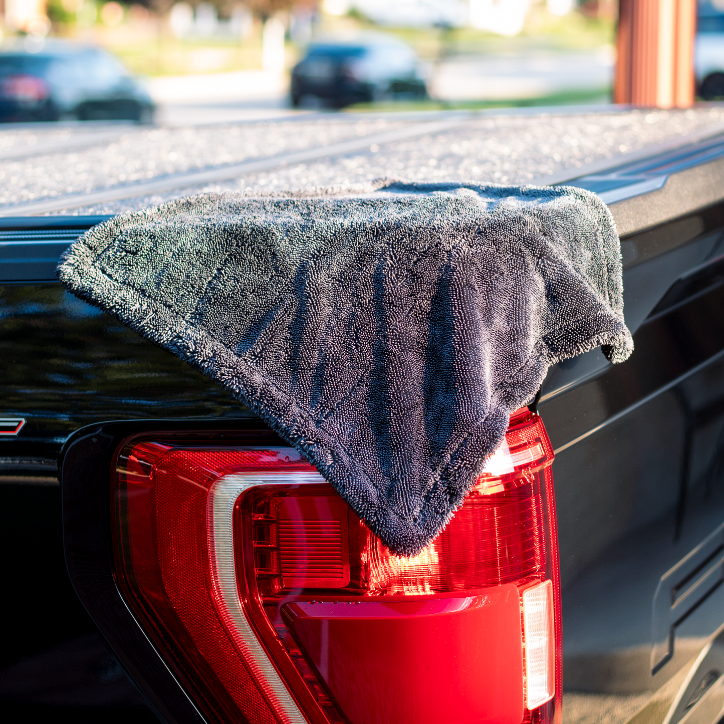 Gray microfiber towel draped over a red car tail light with a blurred background